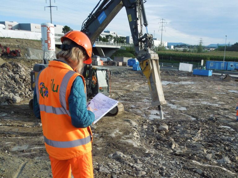 Dienstleistung Umweltbaubegleitung (UBB): Umweltbaubegleitung. Ein Bagger mit Hydraulikhammer zerstösst das steinige Erdreich.